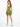 A woman stands in a fitted olive green outfit, showcasing high-waisted shorts and a matching crop top.