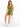 A model sits on a stool wearing a fitted, one-shoulder olive green top paired with matching shorts and white sneakers.