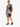 A man stands wearing a short-sleeve shirt and matching shorts with a bold black and white palm leaf pattern.