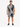 A man stands wearing a short-sleeve shirt and matching shorts with a black and white palm leaf pattern.