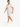 A man wearing a light-colored, short-sleeve shirt and matching shorts, walking in white sneakers.