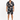 A man stands confidently in a short-sleeve, patterned shirt and matching shorts, paired with white sneakers.