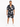 A man stands wearing a short-sleeve, patterned button shirt and matching shorts, paired with white sneakers.