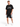A man stands wearing a black oversized t-shirt with graphic text, paired with black shorts featuring a white number.