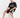 A man sits on a white cube wearing a black graphic t-shirt and black shorts with a white number design.