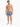 A shirtless man stands in patterned swim shorts with a tropical design, wearing white slide sandals.