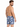 A man with a beard wearing patterned swim shorts featuring tropical leaves, viewed from the back.