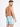 A man with short hair poses from the back, wearing colorful swim trunks featuring a palm tree pattern.