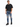 A man stands wearing a black oversized t-shirt, distressed blue jeans, and black sneakers, posing confidently.