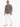 A man stands confidently in a patterned black and white shirt, paired with distressed white jeans and stylish sneakers.