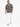 A man walks confidently in white distressed jeans, paired with a black and white patterned shirt and sneakers.
