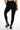 A person wearing form-fitting black leggings and stylish black and white ankle boots, viewed from behind.