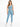 A model wearing a light blue one-shoulder crop top paired with matching leggings and white sneakers.
