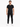 A man stands confidently in a fitted black t-shirt and slim black pants, paired with white sneakers.