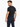 A man with short hair and a beard is wearing a fitted black t-shirt and navy pants, showcasing a casual style.