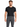 A man wearing a fitted black t-shirt and gray trousers with a chain detail, standing against a white background.