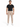 A man stands confidently in a black t-shirt and beige evening pants, paired with white sneakers.