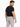 A man wearing a fitted black t-shirt and light gray evening pants, posing with a slight turn and confident expression.