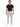 A man stands confidently in a fitted black t-shirt and light gray pants, paired with white sneakers.