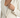 A close-up of a light-colored jacket featuring a deep V-neckline and elegant button details on the sleeves.