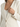 A close-up of a light-colored jacket featuring a deep V-neckline and elegant button details on the sleeves.