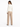 A woman in a fitted cream jacket and beige wide-leg pants stands with her back to the camera, showcasing a sleek silh...