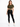 A woman stands confidently in a cropped olive green top tied at the waist, paired with black leggings and white sneak...