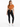 A woman stands confidently in a cropped, rust-colored top tied at the waist, paired with black leggings and white sne...