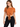 A woman wearing a short-sleeve, rust-colored top with a front knot, paired with black leggings.