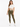 A model poses in a cropped white top with a front knot, paired with olive green leggings and white sneakers.