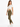 A woman stands in a casual outfit featuring a knotted white crop top and olive green leggings, paired with white snea...