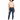 A woman with curly hair wears a cropped beige top and dark blue jeans, paired with white sneakers.