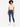A model stands confidently in a cropped beige top, paired with fitted blue jeans and white sneakers.