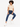 A person with curly hair sits on a stool, wearing a beige cropped top and blue jeans, paired with white sneakers.