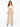 A model poses in a fitted off-the-shoulder top and high-waisted beige wide-leg trousers, showcasing a chic look.