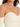 Close-up of a light beige top featuring thin straps and a sweetheart neckline, highlighting ribbed texture.