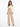 A model poses in a fitted cream top with long sleeves, paired with high-waisted beige trousers and black heels.