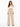 A model poses in a fitted off-the-shoulder top paired with high-waisted, wide-leg beige trousers.
