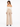 A woman with long hair wears a fitted off-the-shoulder top and high-waisted beige pants, showcasing a stylish back view.