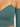 Close-up of a ribbed, teal top featuring thin straps and an off-the-shoulder design with a small pocket.