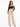 A woman poses in a fitted black off-the-shoulder top paired with high-waisted beige wide-leg trousers.