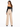 A woman with long hair wears a black off-the-shoulder top and beige wide-leg pants, showcasing a stylish back view.