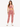 A woman models a soft, pink, cropped top with a draped neckline and matching jogger pants, paired with white sneakers.