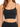 A close-up of a woman wearing a black, sleeveless, cropped top with thin straps and a subtle shimmer.