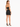 A woman stands in a fitted black crop top and matching skirt, showcasing a sleek silhouette and strappy heels.