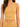 A model wearing a ribbed, one-shoulder, mustard-colored crop top paired with a matching bottom.