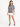 A model poses in a gray tie-dye tee featuring playful hand graphics, paired with a white skirt and black heels.
