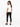 A woman with long hair wears a plain white tee, black skinny jeans, and black sneakers, posing from the back.