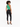A woman with curly hair wears a fitted green ribbed top and black skinny jeans, paired with black heels.