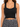 Black ribbed crop top with wide straps, paired with a patterned pleated skirt.